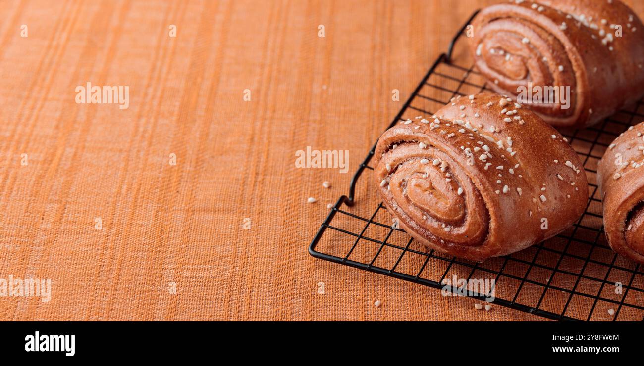 Korvapuusti, petits pains finlandais traditionnels à la cannelle et à la cardamome, petits pains frais sur la grille métallique, dessert sucré Suède et Finlande, bannière horizontale Banque D'Images