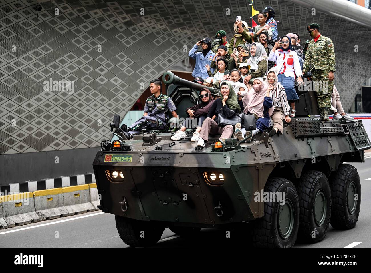 Jakarta, Indonésie. 5 octobre 2024. Des gens montent dans la rue avec des soldats des Forces armées nationales indonésiennes (TNI) à bord d’un véhicule militaire après le défilé militaire du 79e anniversaire de la TNI à Jakarta, Indonésie, le 5 octobre 2024. Crédit : Agung Kuncahya B./Xinhua/Alamy Live News Banque D'Images