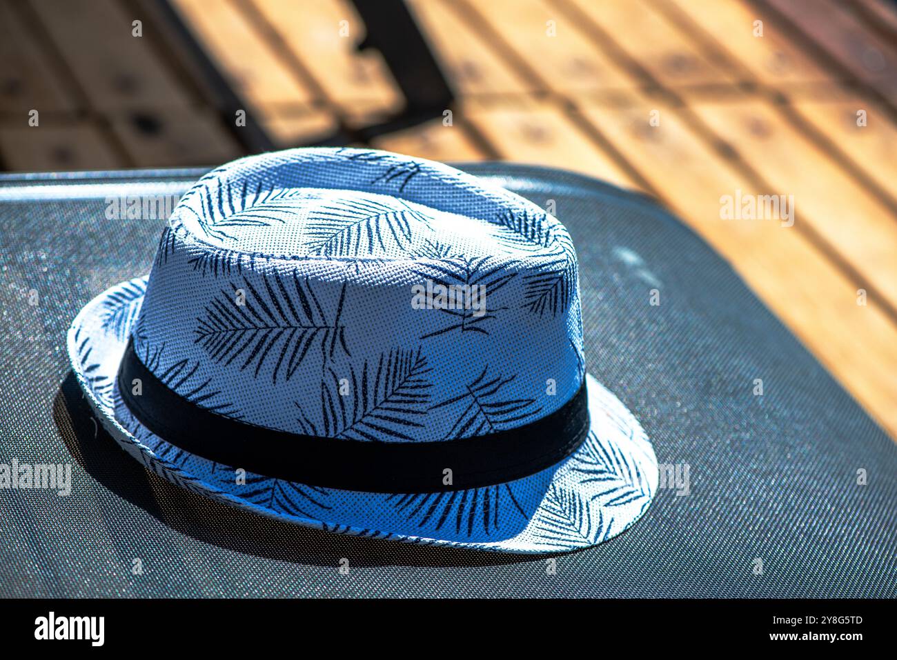 Une scène détendue avec un chapeau d'homme posé sur un transat, capturant l'essence d'une journée de détente à la plage ou au bord de la piscine. Banque D'Images