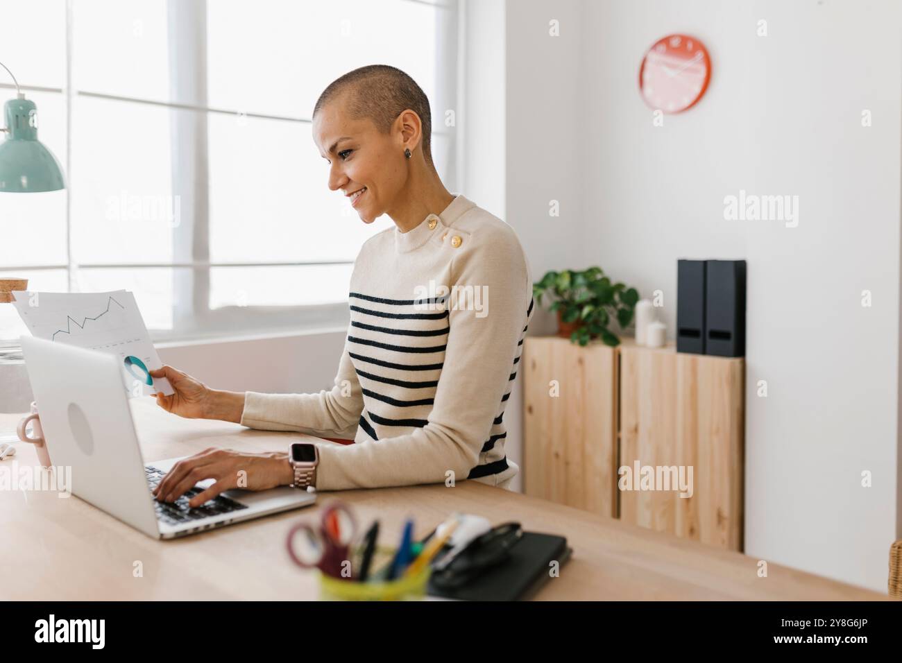 Femme d'affaires travaillant avec un ordinateur portable tout en tenant le document de paperasse sur le bureau Banque D'Images Femme d'affaires travaillant avec un ordinateur portable tout en tenant le document de paperasse sur le bureau Banque D'Images