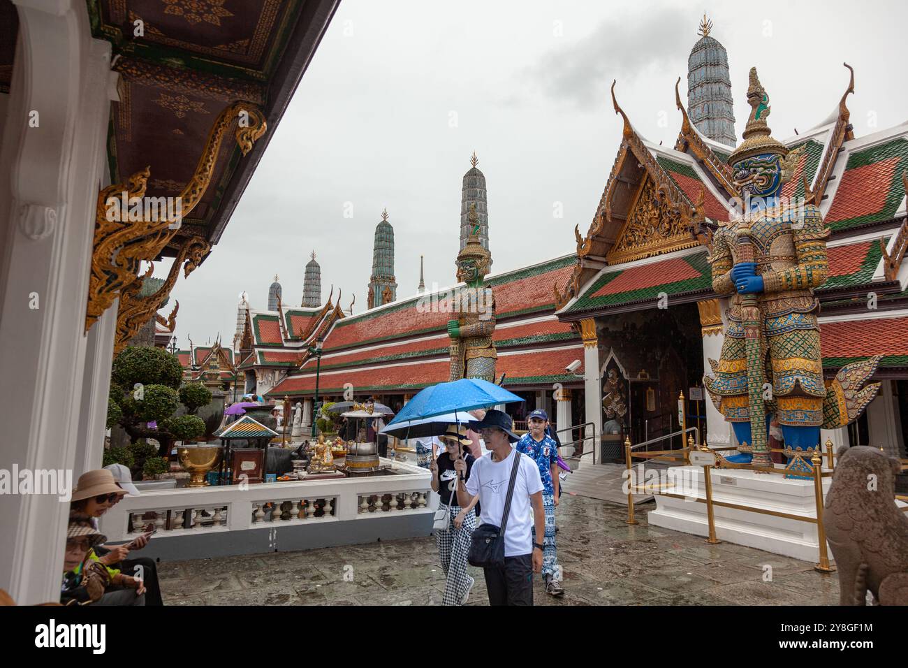 Les visiteurs avec des parapluies explorent Wat Phra Kaew, également connu sous le nom de Temple du Bouddha d'émeraude, situé dans le complexe du Grand Palais à Bangkok, en Thaïlande Banque D'Images