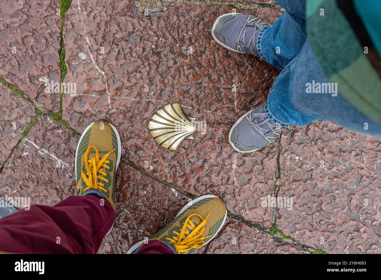 Deux randonneurs debout devant une coquille de Saint-Jacques encastrée dans le sol à Oviedo, un symbole montrant la route de pèlerinage à Santiago de Compostelle, en Espagne Banque D'Images