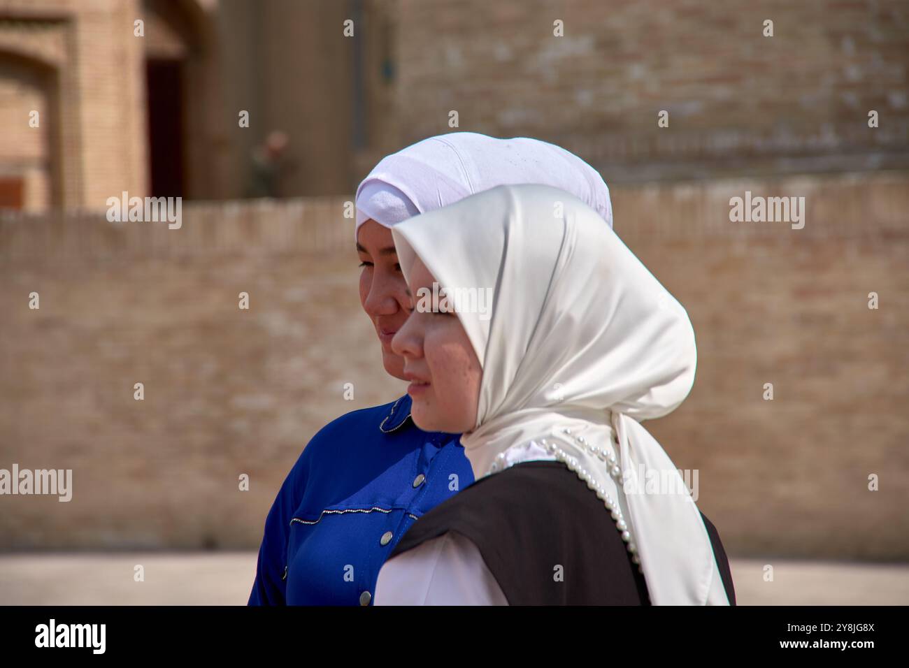 Boukhara, Ouzbékistan ; septembre,19,2024:deux jeunes femmes ouzbèkes ornées d'élégants voiles blancs, sur fond pittoresque de Boukhara Banque D'Images