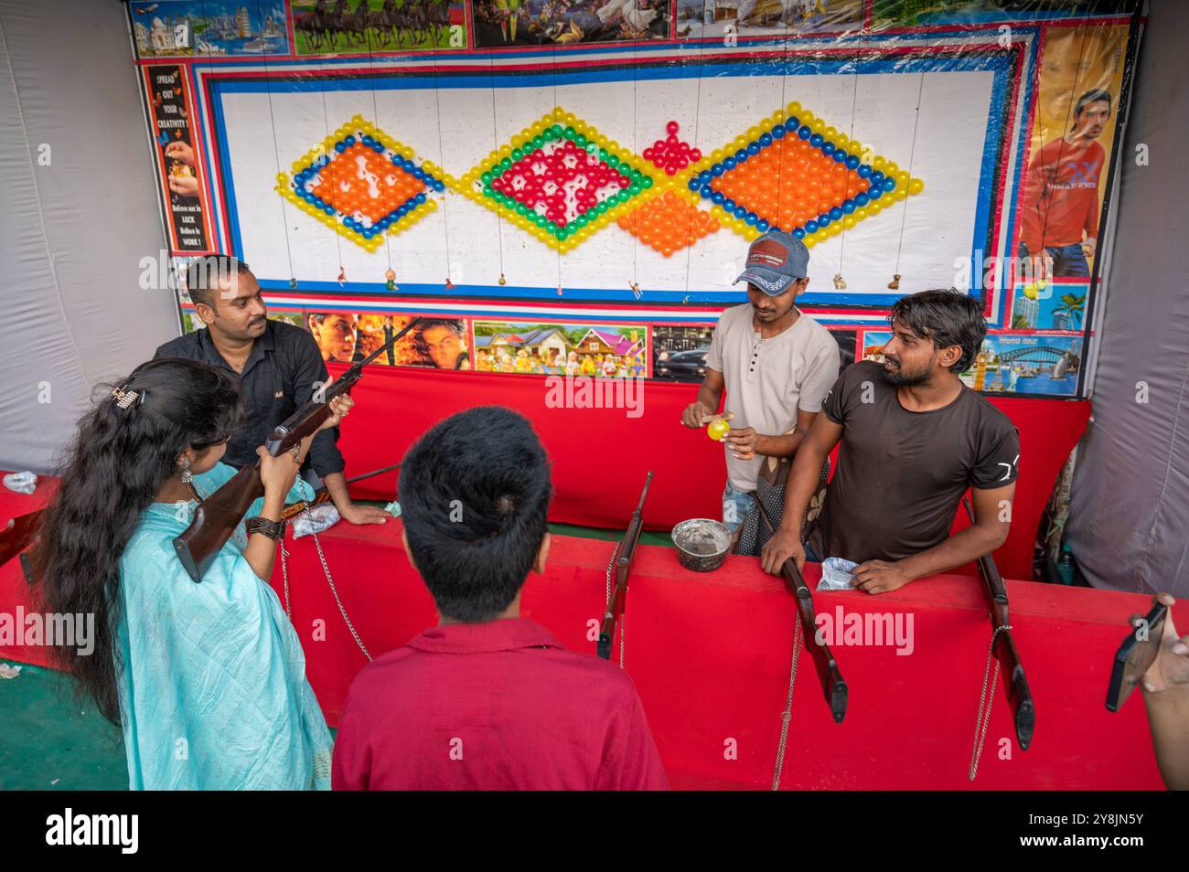 New Delhi, Inde. 05 octobre 2024. Une jeune fille tire sur cible avec un pistolet à air comprimé sur un stand de tir de ballon pendant la foire de Dussehra au Red Fort Ground. La Dussehra Mela est une célébration vibrante organisée pendant le festival hindou de Dussehra, symbolisant la victoire du bien sur le mal. Les foires à Red Fort Ground sont particulièrement populaires, attirant de grandes foules. Les gens peuvent profiter de la nourriture délicieuse, monter sur de grandes balançoires, et regarder les spectacles de Ramleela. (Photo de Pradeep Gaur/SOPA images/SIPA USA) crédit : SIPA USA/Alamy Live News Banque D'Images