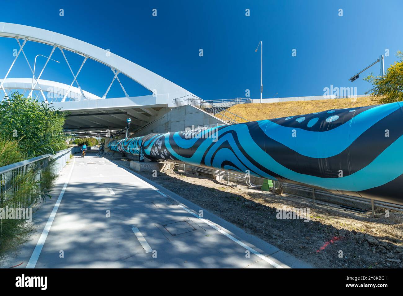 Sydney, Australie, 6 octobre 2024. Un pipeline de 800 mètres recouvert de graffitis a été renouvelé en une œuvre d’art inspirée des Premières Nations. Le pipeline longe Airport Drive et Alexandra canal à l'aéroport de Sydney pour transporter l'eau de l'usine de dessalement de Sydney vers d'autres parties de la ville. Il a été conçu par Dennis Golding et Carmen Glynn-Braun de Re-Right. JO Breneger et Leia Sidery ont peint le pipeline. Sa conception est basée sur les paysages des régions de Bidjigal, Gadigal et Dharawal. Sur la photo : la murale vue depuis Twin Arch Bridge. Crédit : Robert Wallace / Wallace Media Network / Alamy Live News Banque D'Images