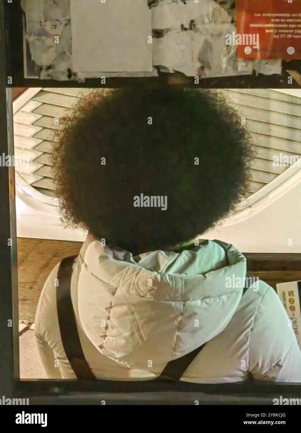 Portrait urbain sans visage : jeune personne à la coiffure afro attendant le bus Banque D'Images