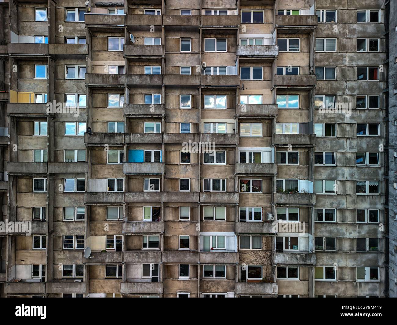 Gros plan d'une façade d'immeuble de l'ère soviétique à Łódź, en Pologne, montrant une grille de balcons et de fenêtres en béton altérés Banque D'Images