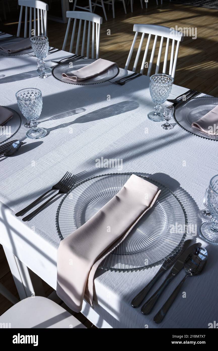 Verre de cristal sur la table dans une salle de banquet lumineuse aux parois de verre. Photo prise pendant la journée, avec la lumière du soleil. Banque D'Images