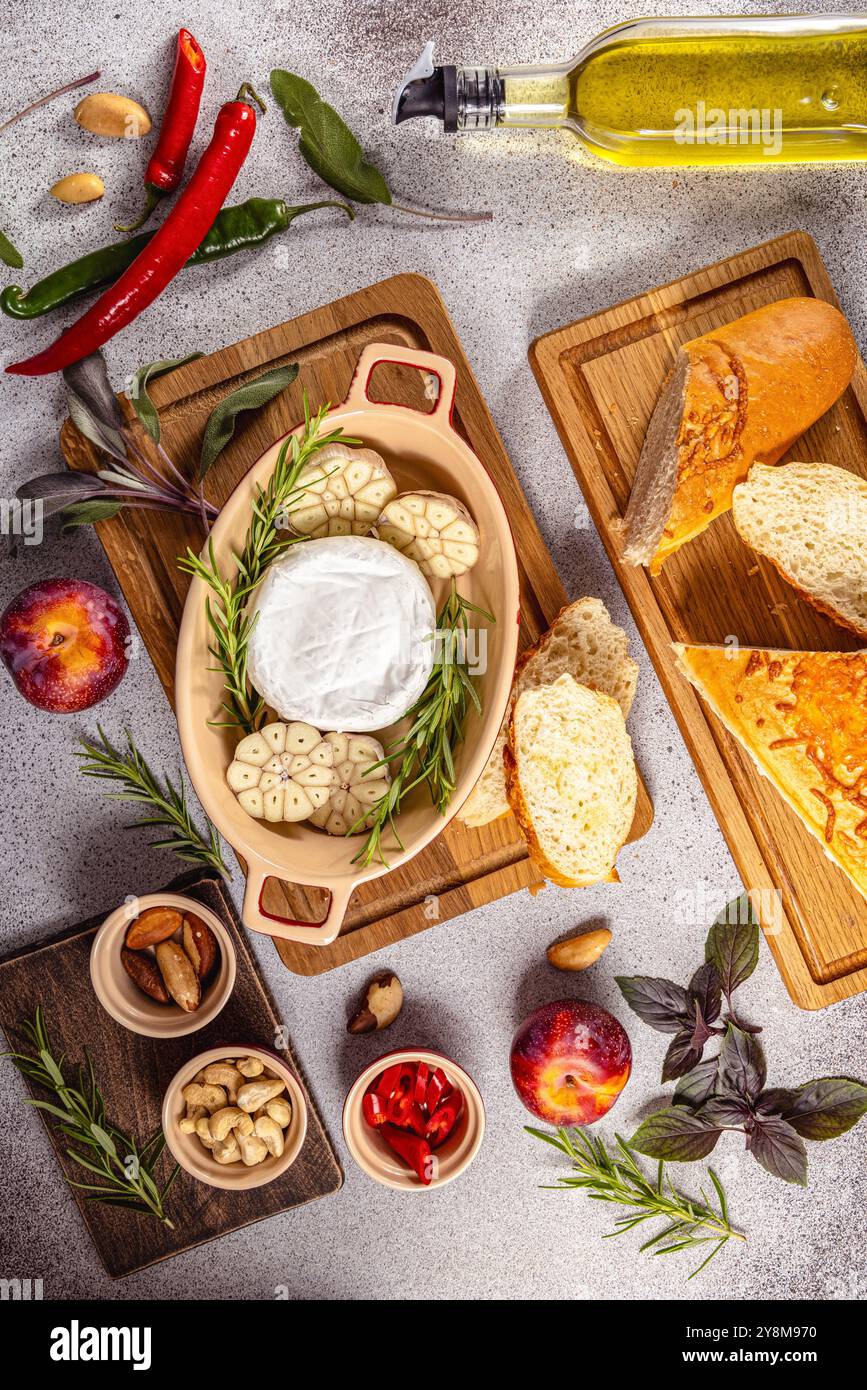 Ingrédients pour un délicieux camembert cuit au four entouré d'herbes fraîches, d'épices et de noix sur un fond clair Banque D'Images