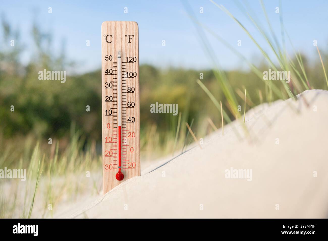 Thermomètre en bois à échelle celsius et fahrenheit dans le sable. Température ambiante plus 2 degrés. Chaude journée d'été Banque D'Images