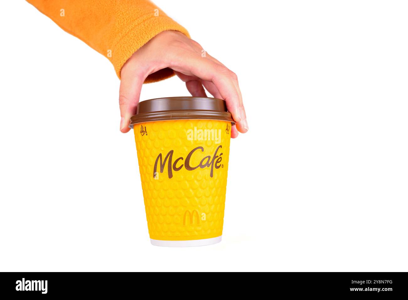Kiev, Ukraine - 24 septembre 2024 : gros plan d'une main saisissant une tasse de café McCafé jaune avec un design texturé et un logo, idéal pour la marque, c Banque D'Images