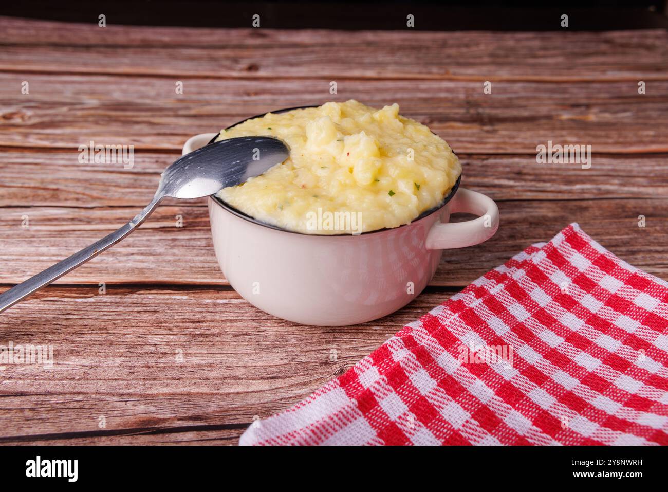 Une main ramasse une purée de pommes de terre moelleuse dans un bol, mettant en valeur la chaleur des réunions de famille le jour de Thanksgiving Banque D'Images