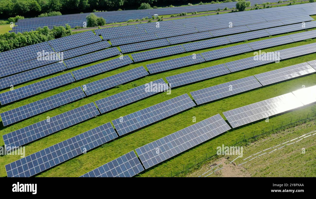 Cette vue aérienne époustouflante capture un vaste champ solaire, mettant en valeur une vaste gamme de panneaux solaires exploitant l'énergie du soleil. La grille ordonnée reposait Banque D'Images