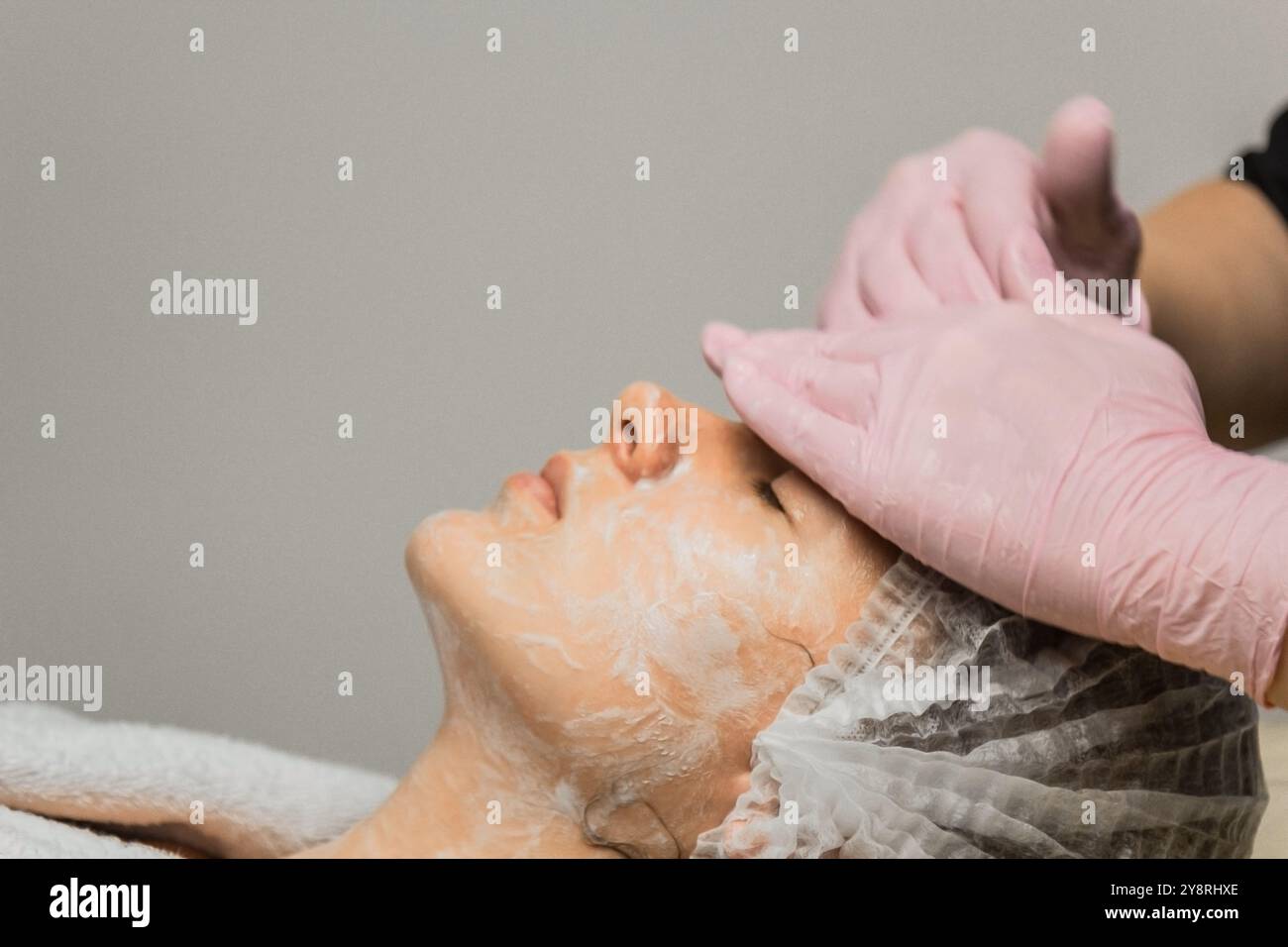 concept esthéticienne. Les mains d'un cosmétologue mettent de la crème sur le visage d'une femme. Esthéticienne applique une crème sur le visage de la fille. Banque D'Images