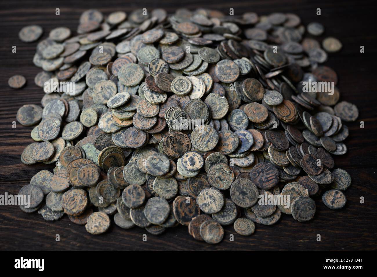 Pile de nombreuses pièces de monnaie romaines antiques sur une table en bois foncé, vieil argent en bronze, fond vintage. Concept d'antique, Empire, Rome, texture, civilisation a Banque D'Images