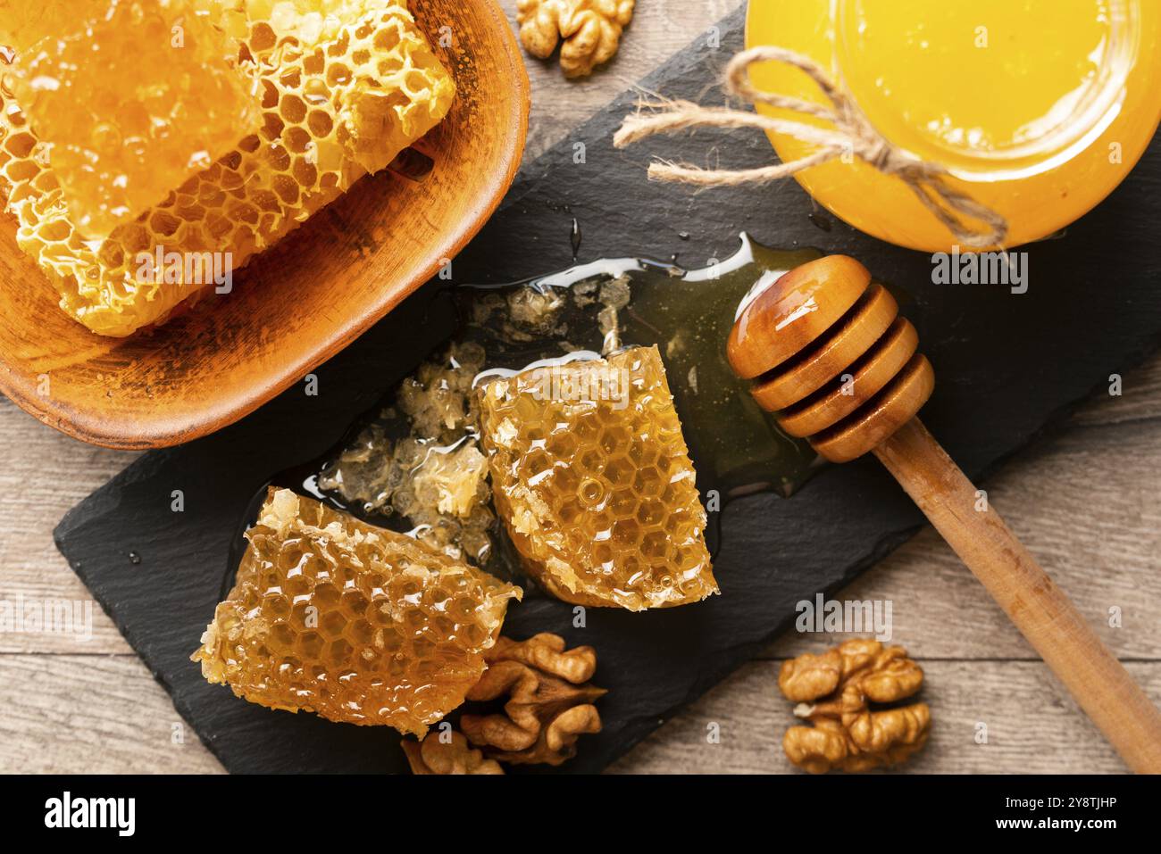 Nid d'abeille sur plateau en ardoise avec miel et noix sur la table de cuisine Banque D'Images