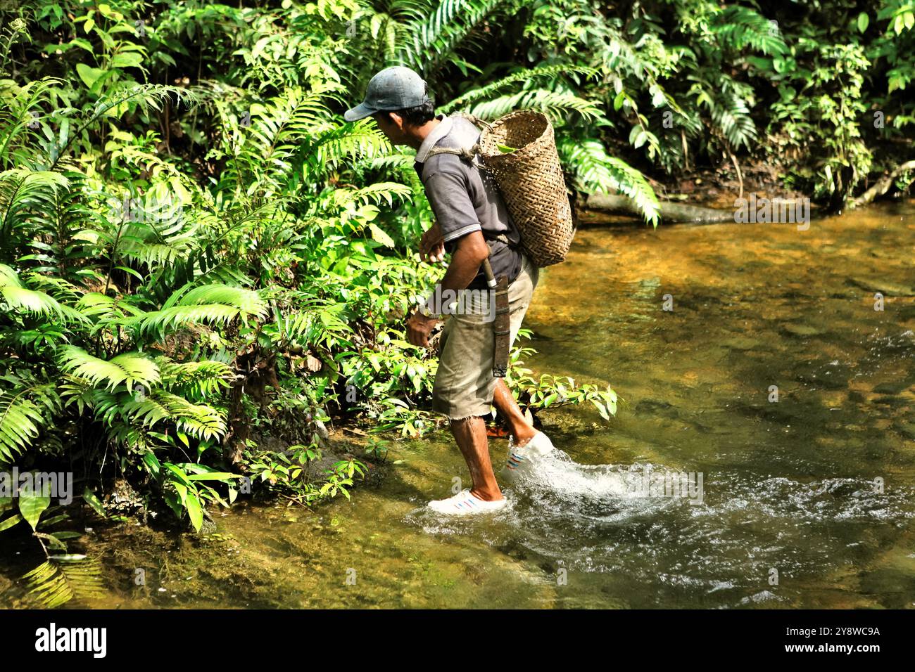 Un homme traversant un ruisseau pendant une affectation communautaire à une source d'eau potable et à une installation d'eau à Kapuas Hulu, Kalimantan occidental, Indonésie. Banque D'Images