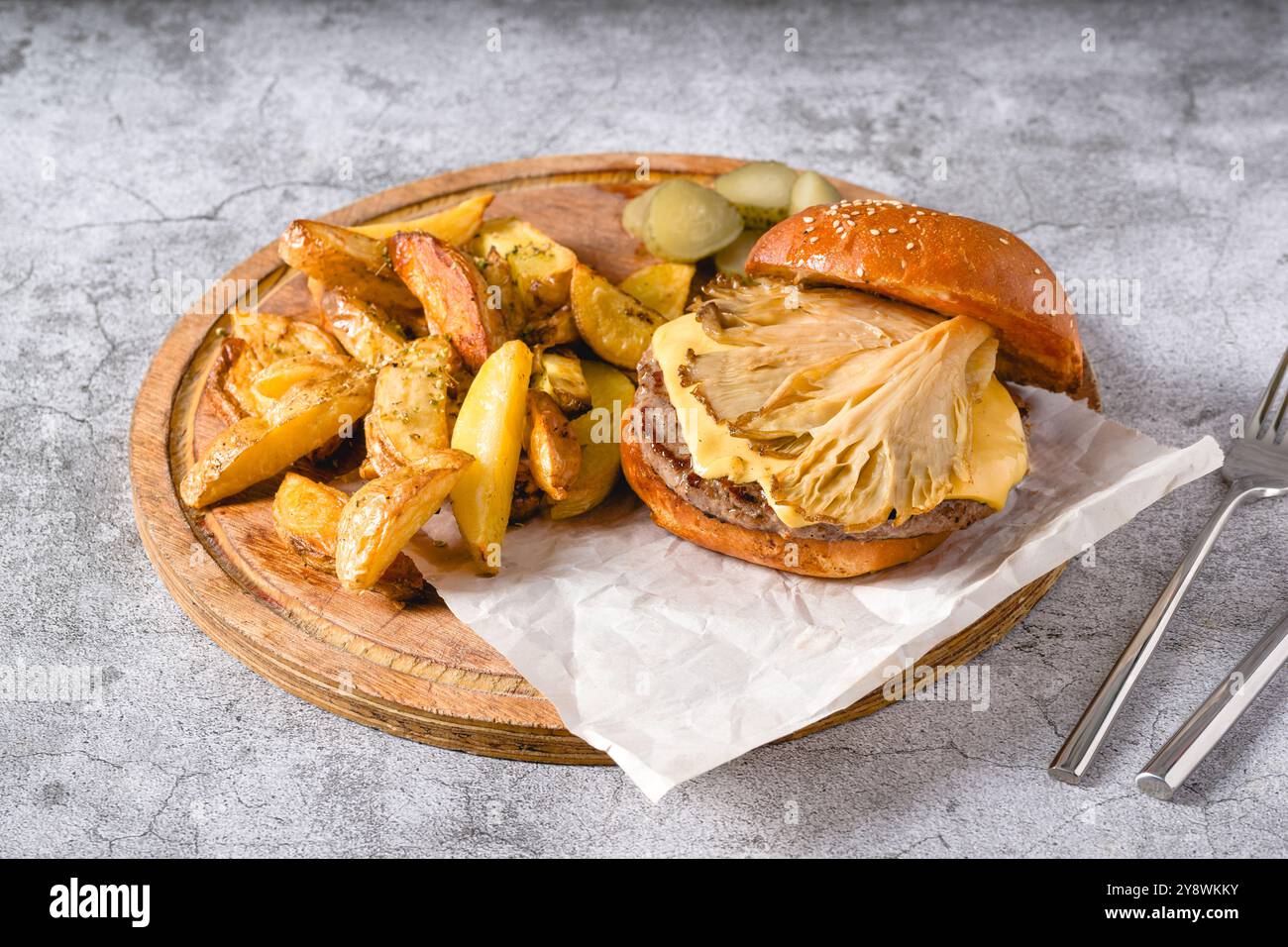 Hamburger avec des huîtres et du fromage cheddar sur une planche à découper en bois Banque D'Images