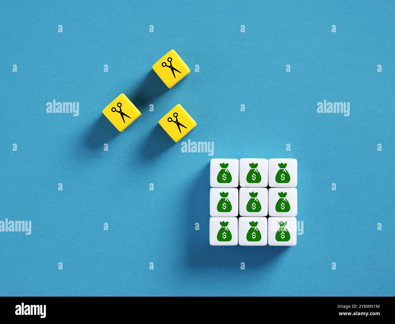 Image conceptuelle des coupes budgétaires, en utilisant des ciseaux et des icônes de sac d'argent sur des cubes colorés Banque D'Images