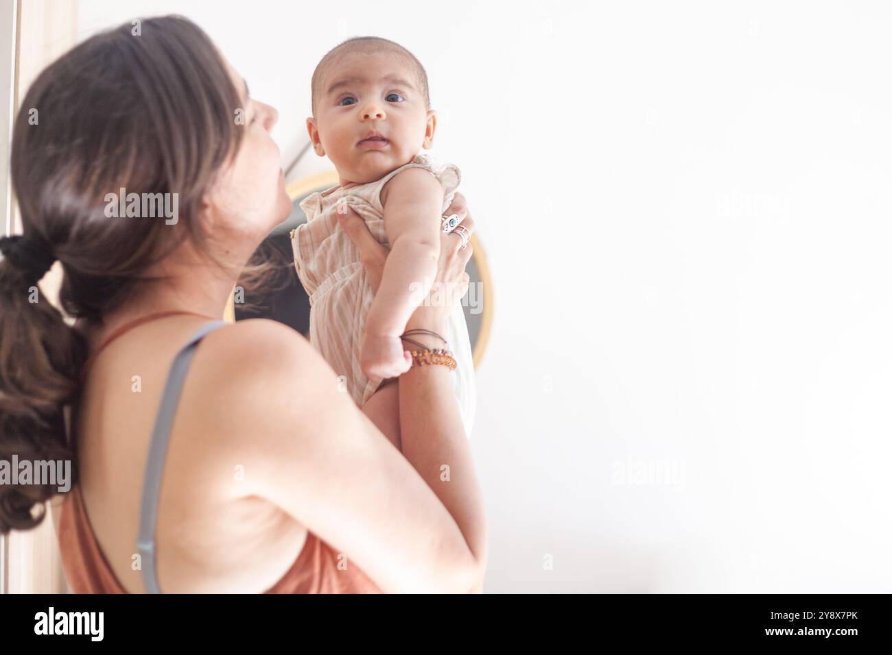 Une femme tient un bébé dans ses bras. Le bébé porte une tenue blanche Banque D'Images