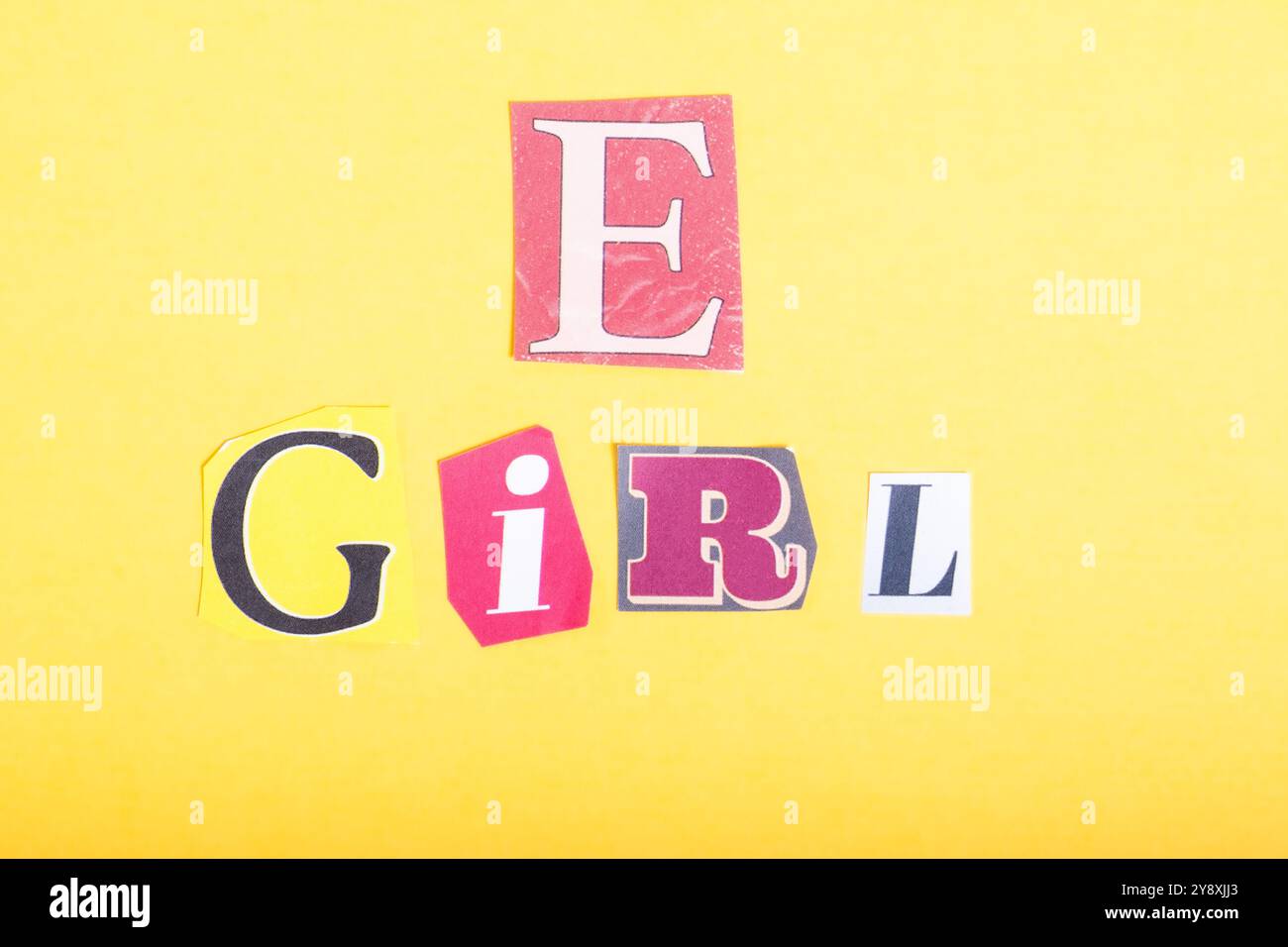 Phrase E fille épelée dans la typographie de style journal découpée, isolée sur fond jaune. Banque D'Images