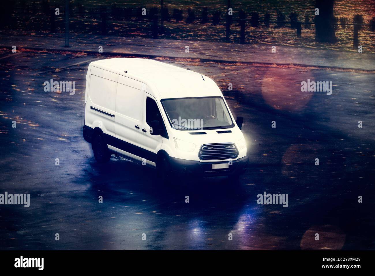 Le fourgon de livraison blanc transporte des marchandises par un soir sombre d'automne, vue surélevée. Banque D'Images