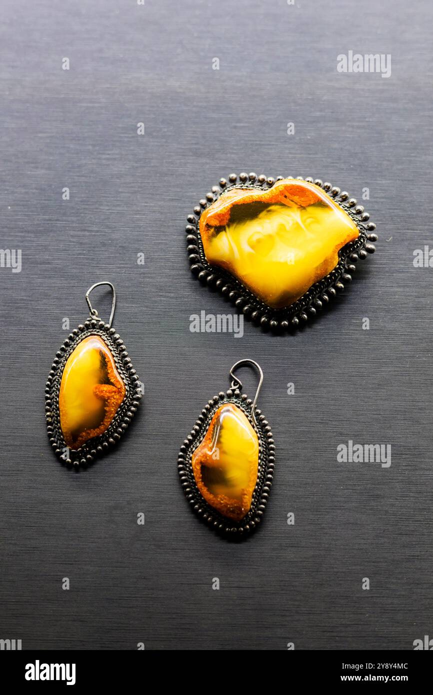Une broche magnifiquement conçue et une paire de boucles d'oreilles élégantes sont assis sur une surface noire élégante, créant un contraste saisissant Banque D'Images Une broche magnifiquement conçue et une paire de boucles d'oreilles élégantes sont assis sur une surface noire élégante, créant un contraste saisissant Banque D'Images