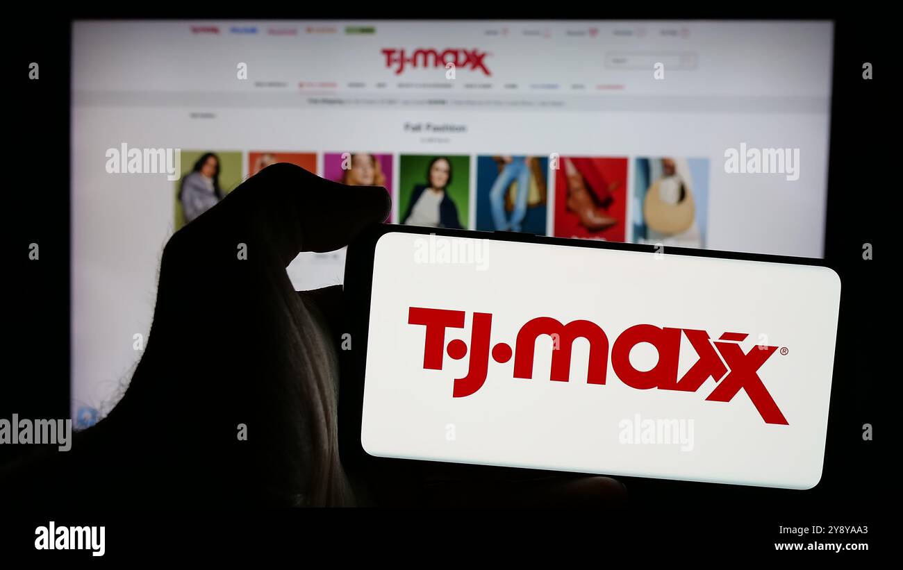 Personne tenant un smartphone avec le logo de la société américaine de magasin de rabais TJ Maxx sur l'écran en face du site Web. Concentrez-vous sur l'affichage du téléphone. Banque D'Images