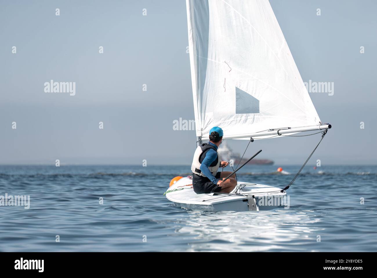 Voilier canot seul par une journée ensoleillée, un jeune homme navigue sur les vagues, sentant le vent dans ses voiles, profitant de la liberté et des loisirs sur l'eau Banque D'Images