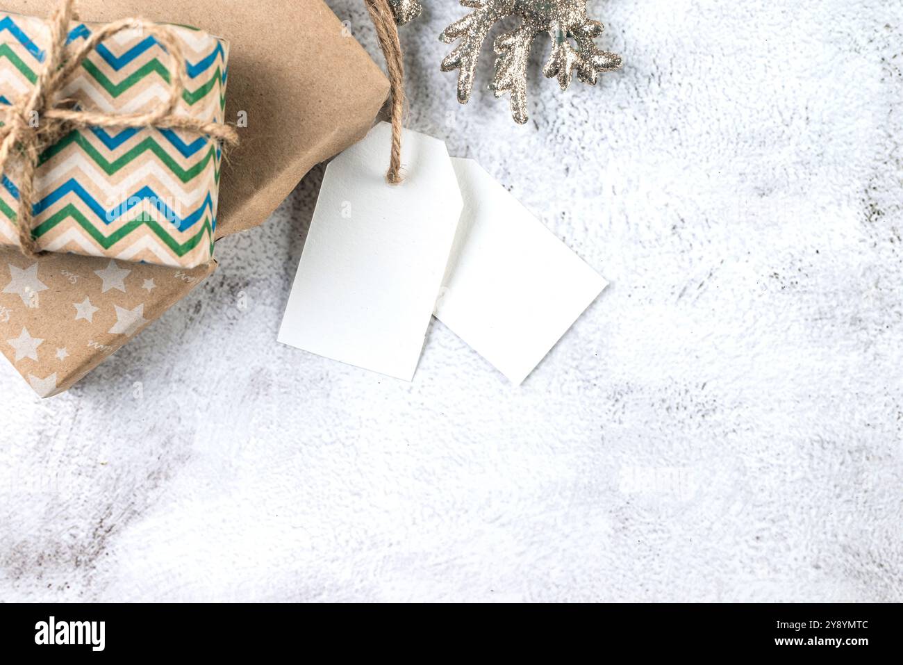 Étiquette de papier blanc sur les boîtes de cadeaux d'artisanat et décor de Noël sur fond conkrete gris. Maquette de carte de voeux de Noël. Banque D'Images