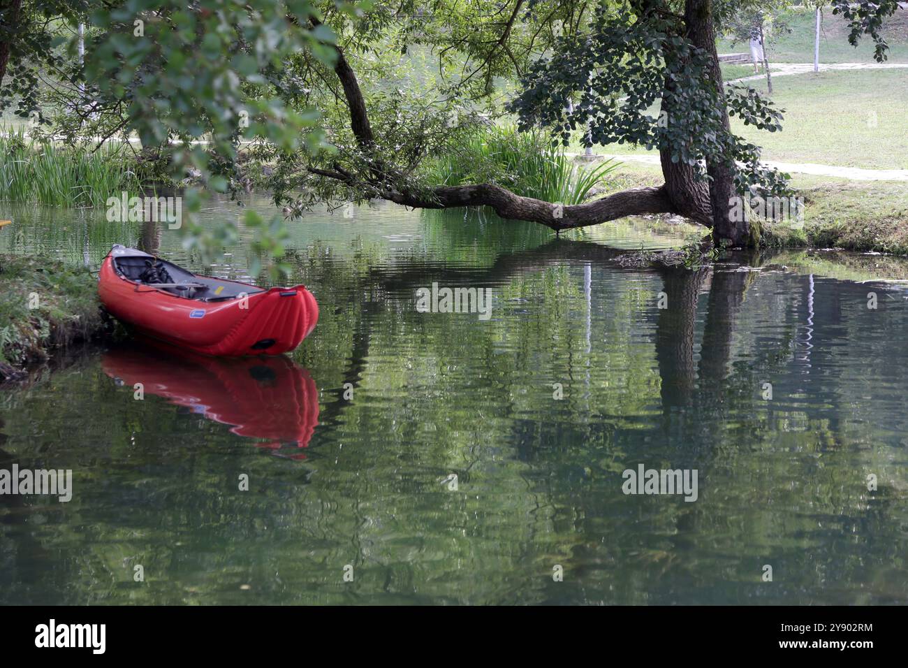 Bateau en caoutchouc rouge sur le lac avec belle réflexion et contraste. Banque D'Images