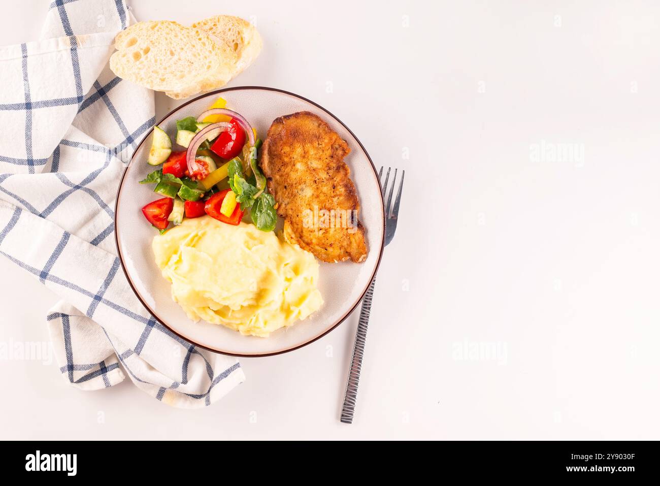 Steak de poulet frit ou schnitzel avec purée de pommes de terre et salade de légumes dans une assiette sur une table blanche Banque D'Images