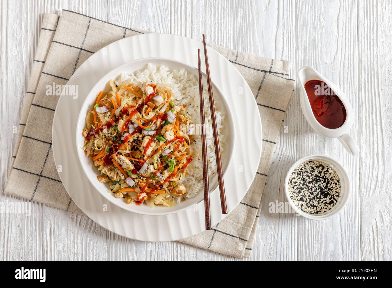 roulé aux œufs de tofu, chou sautés, tofu émietté assaisonné servi dans une sauce sucrée et salée servie sur du riz dans un bol sur une table en bois blanc avec des côtelettes Banque D'Images