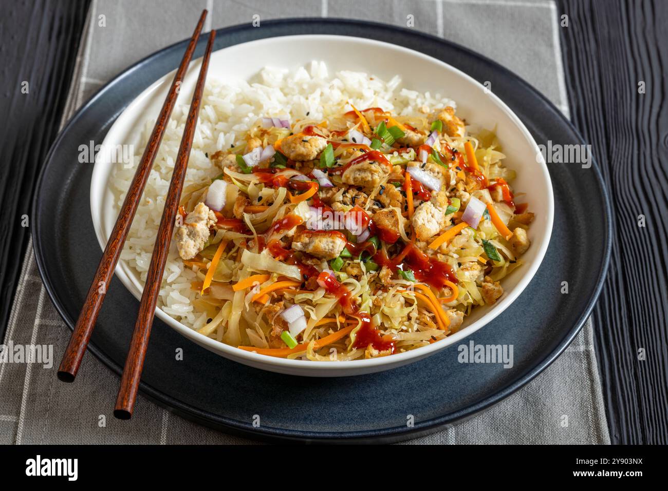 roulé aux œufs de tofu, chou sautés, tofu émietté assaisonné servi dans une sauce sucrée et salée servi sur du riz dans un bol sur une table en bois noir avec des côtelettes Banque D'Images
