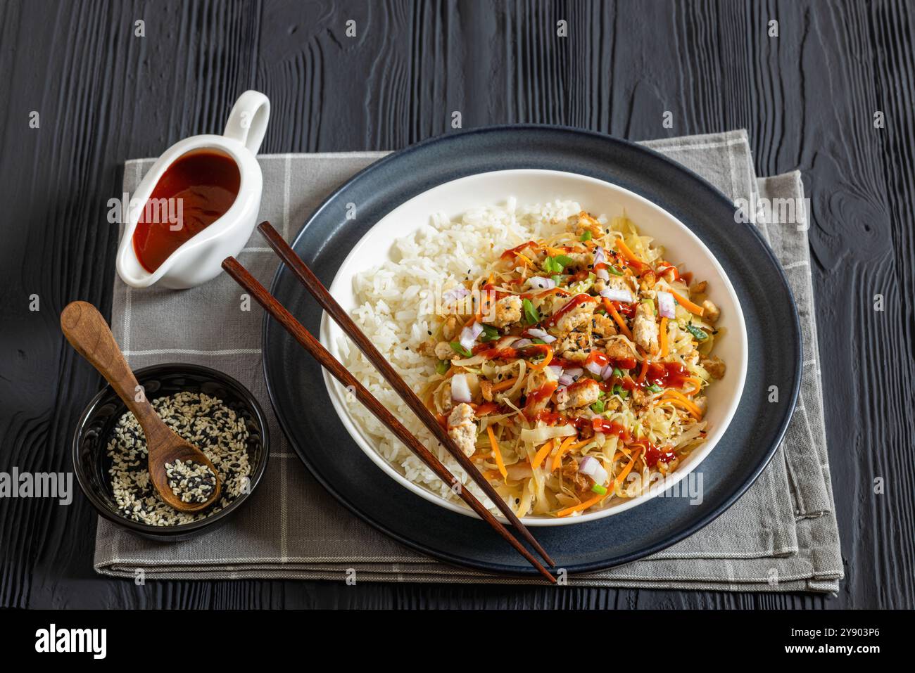 roulé aux œufs de tofu, chou sautés, tofu émietté assaisonné servi dans une sauce sucrée et salée servi sur du riz dans un bol sur une table en bois noir avec des côtelettes Banque D'Images