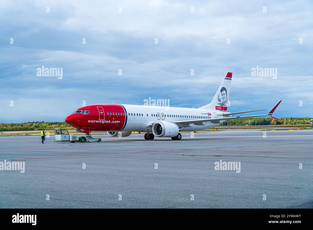 Boeing 737-800 norvégien à l'aéroport de Stockholm Arlanda sur l'aire de trafic, en repoussage. Nuageux, lumière vive. Banque D'Images