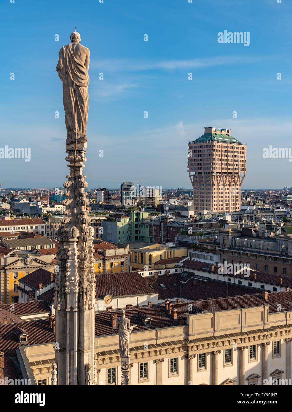 Photo d'une flèche et d'une statue du toit du Duomo di Milano ou de la cathédrale de Milan surplombant la Tour Velasca. Banque D'Images