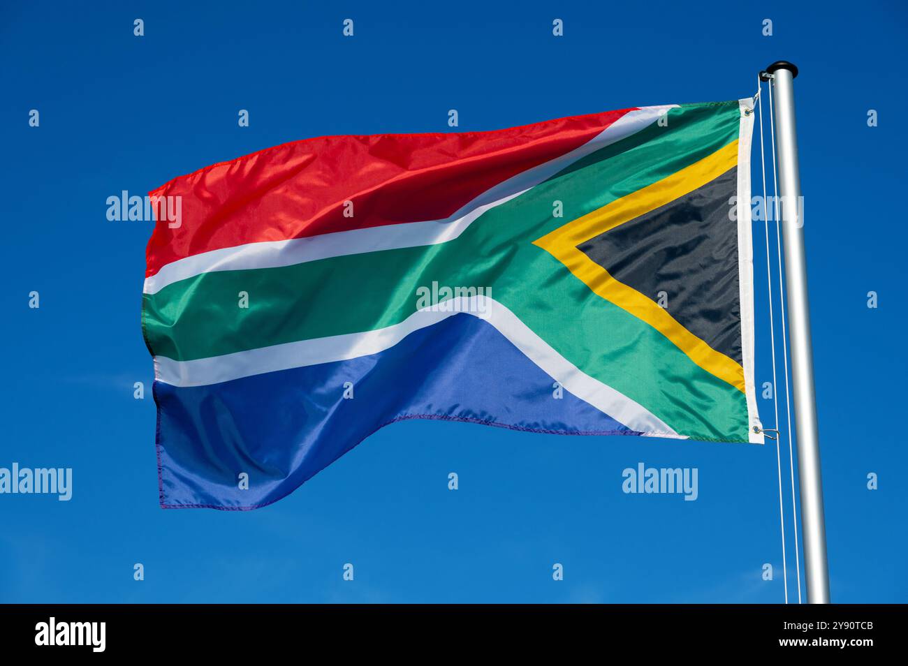 Le drapeau de l'Afrique du Sud bat dans le vent contre un ciel bleu sans nuages Banque D'Images