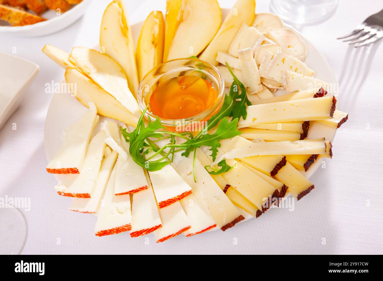 Assiette avec différents types de fromage et une tasse de miel Banque D'Images