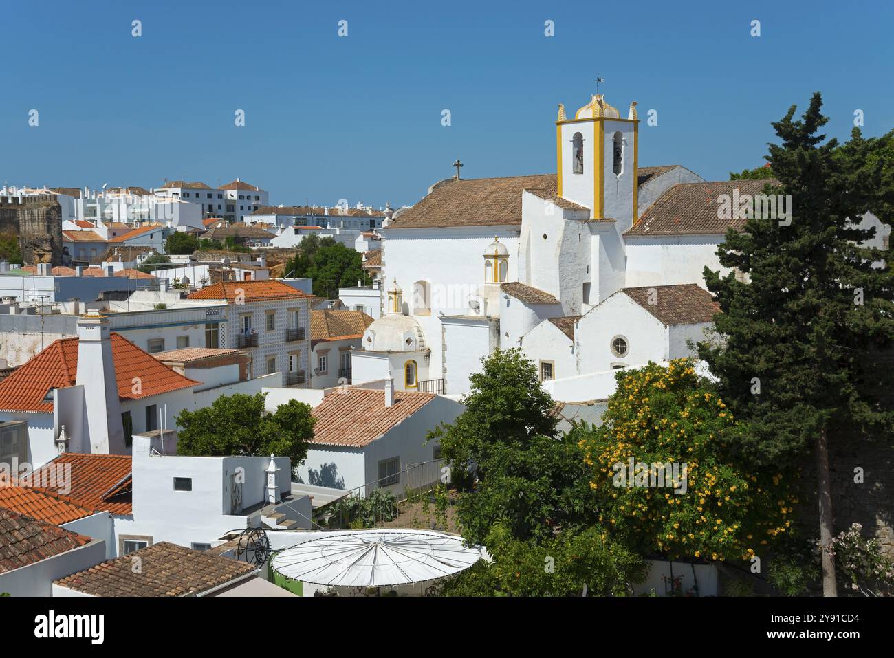 Église blanche entourée de bâtiments classiques et d'arbres sous un ciel bleu vif, vue depuis le château, Castelo, église Igreja de Santiago, Tavira, Fa Banque D'Images