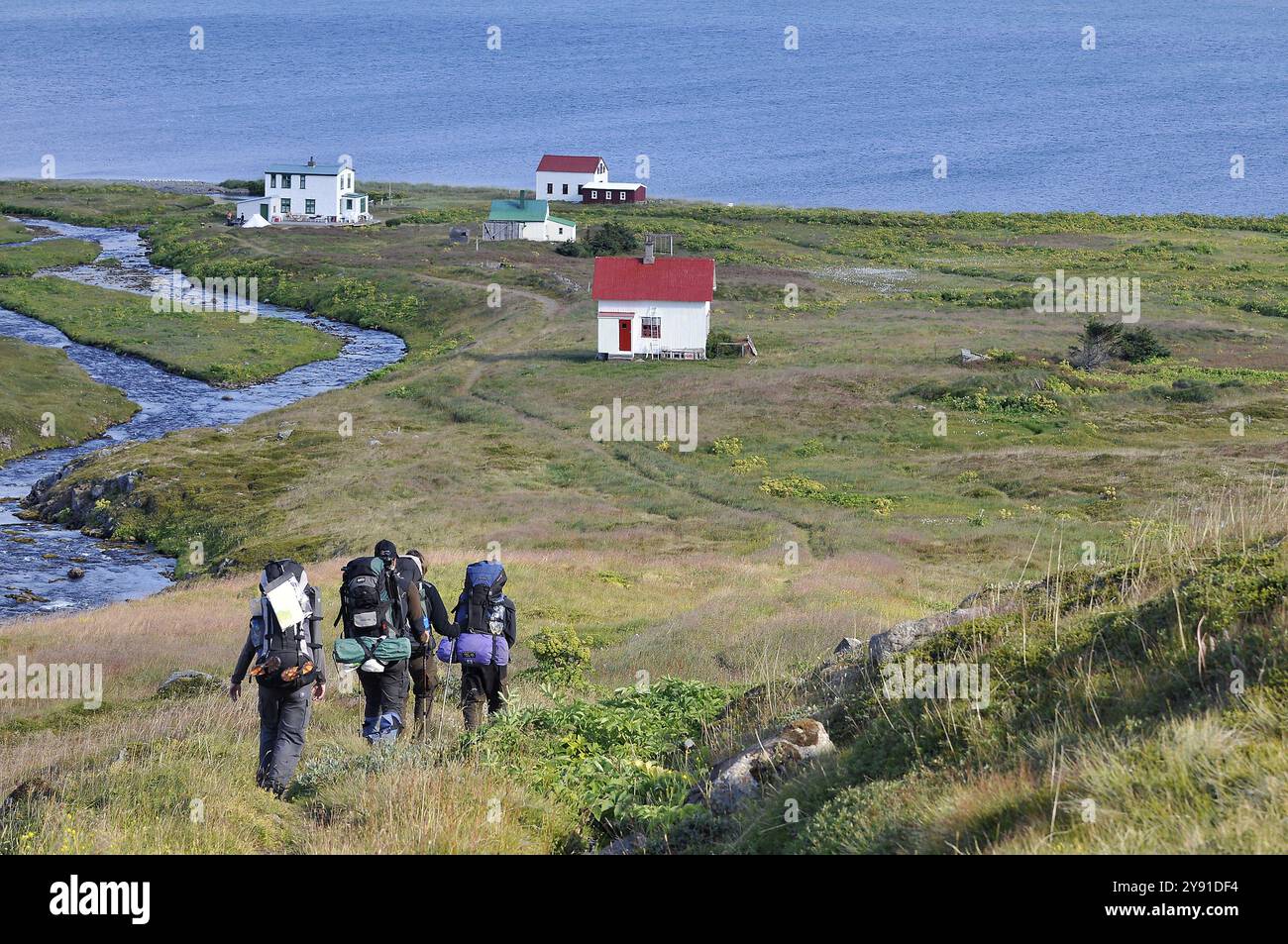 Groupe de randonneurs avec sacs à dos lourds, vieilles maisons, Hesteyri, HesteyrarfjoerÃ°ur ou Hesteyrarfjoerdur, paradis des randonnées Hornstrandir, Westfjords, Islande Banque D'Images