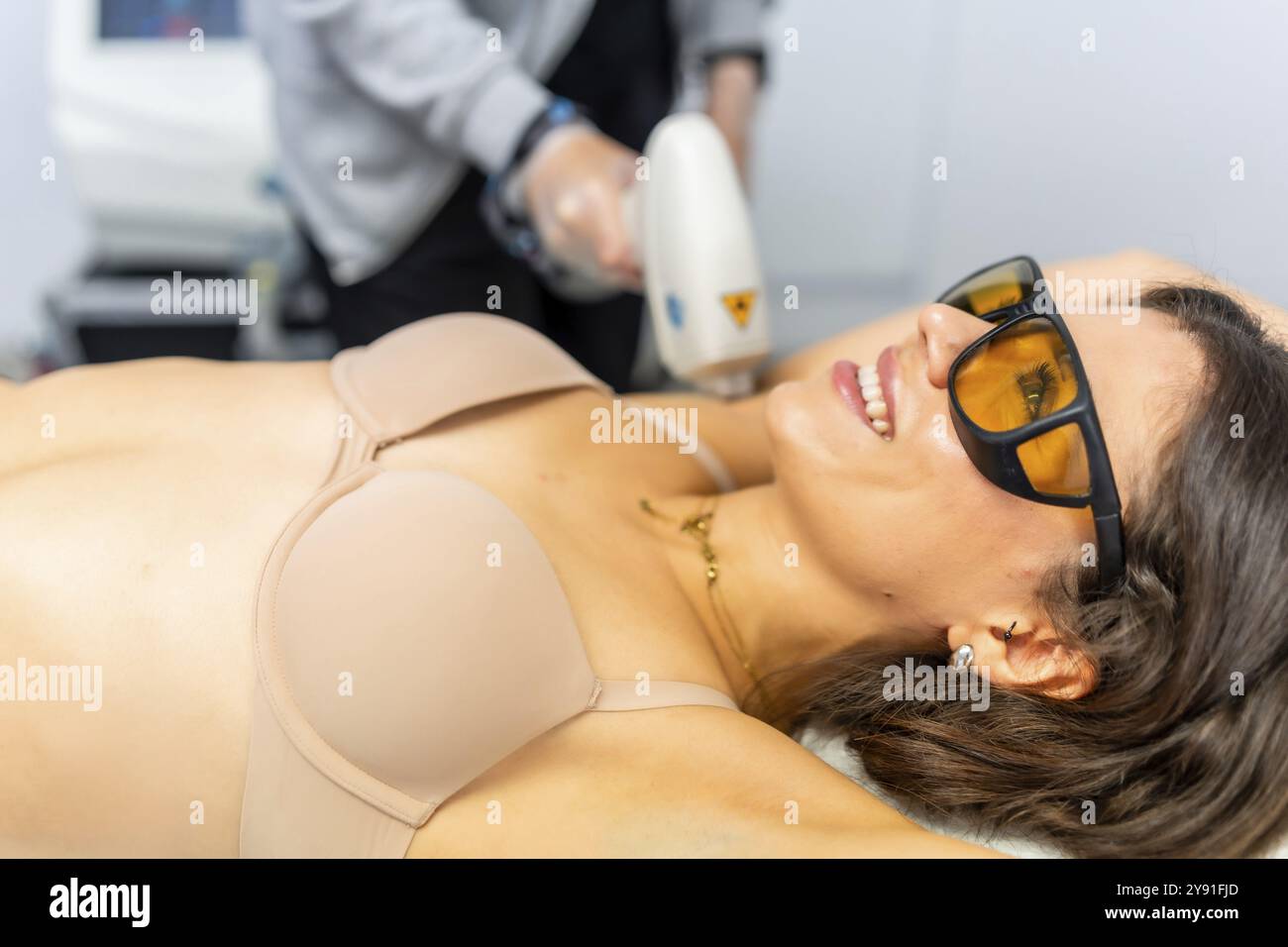 Belle et attrayante femme adulte recevant un traitement épilatoire sur l'aisselle couchée sur la clinique Banque D'Images