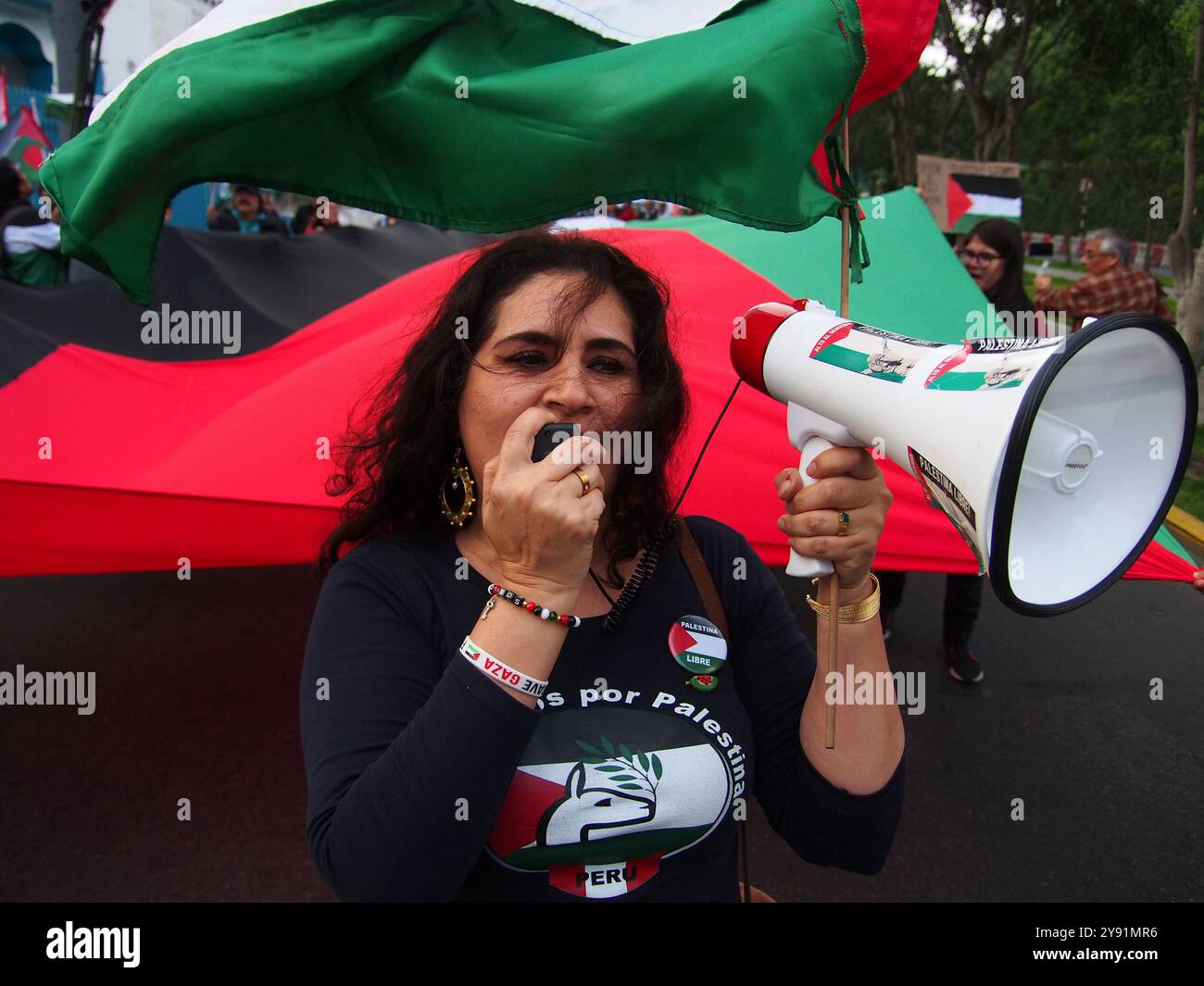 Lima, Pérou. 07 octobre 2024. Femme avec haut-parleur à la tête d'un drapeau palestinien géant lorsque des dizaines de manifestants sont descendus dans les rues de Lima en solidarité avec la Palestine et le Liban pour marquer le premier anniversaire de la guerre entre Israël et le Hamas, qui a commencé le 7 octobre 2023, lorsque le Hamas a tué et enlevé des Israéliens au festival de musique Nova. Crédit : Agence de presse Fotoholica/Alamy Live News Banque D'Images