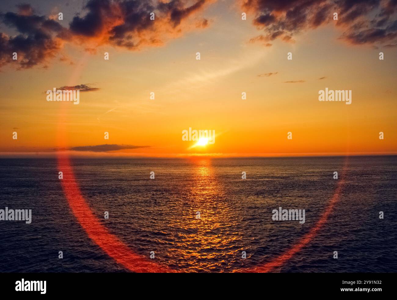 Photographie d'un coucher de soleil du ciel océanique avec halo de lumière parasite, coucher de soleil, nuages et océan. Banque D'Images