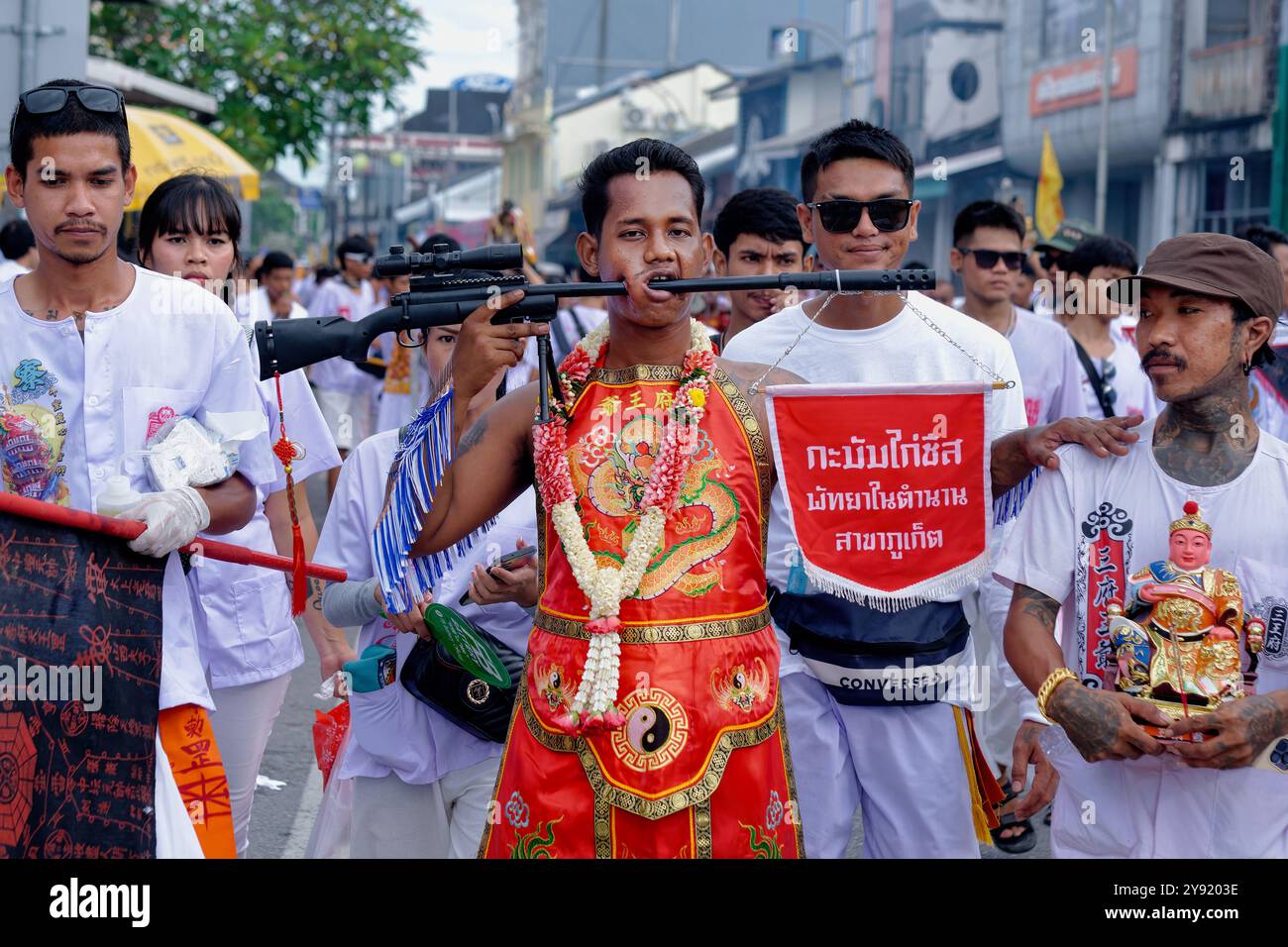 Dans une procession pendant le Festival végétarien annuel à Phuket Town, Thaïlande, un participant montre un fusil poussé à travers une coupure dans sa joue Banque D'Images