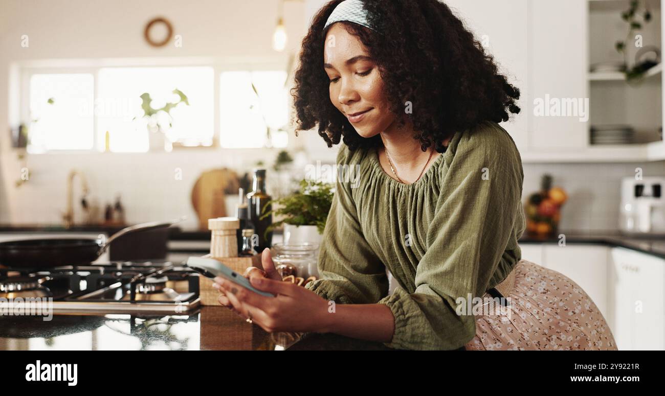 Cuisine, cuisine et femme avec smartphone, dactylographie et idées pour le petit déjeuner, numérique et planification. Maison, web et personne avec mobile, contempler et Banque D'Images