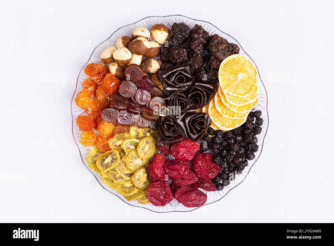 Un assortiment de fruits secs, y compris des oranges, des mûres et des rouleaux de fruits artistiques en forme de rose sur une assiette décorative Banque D'Images