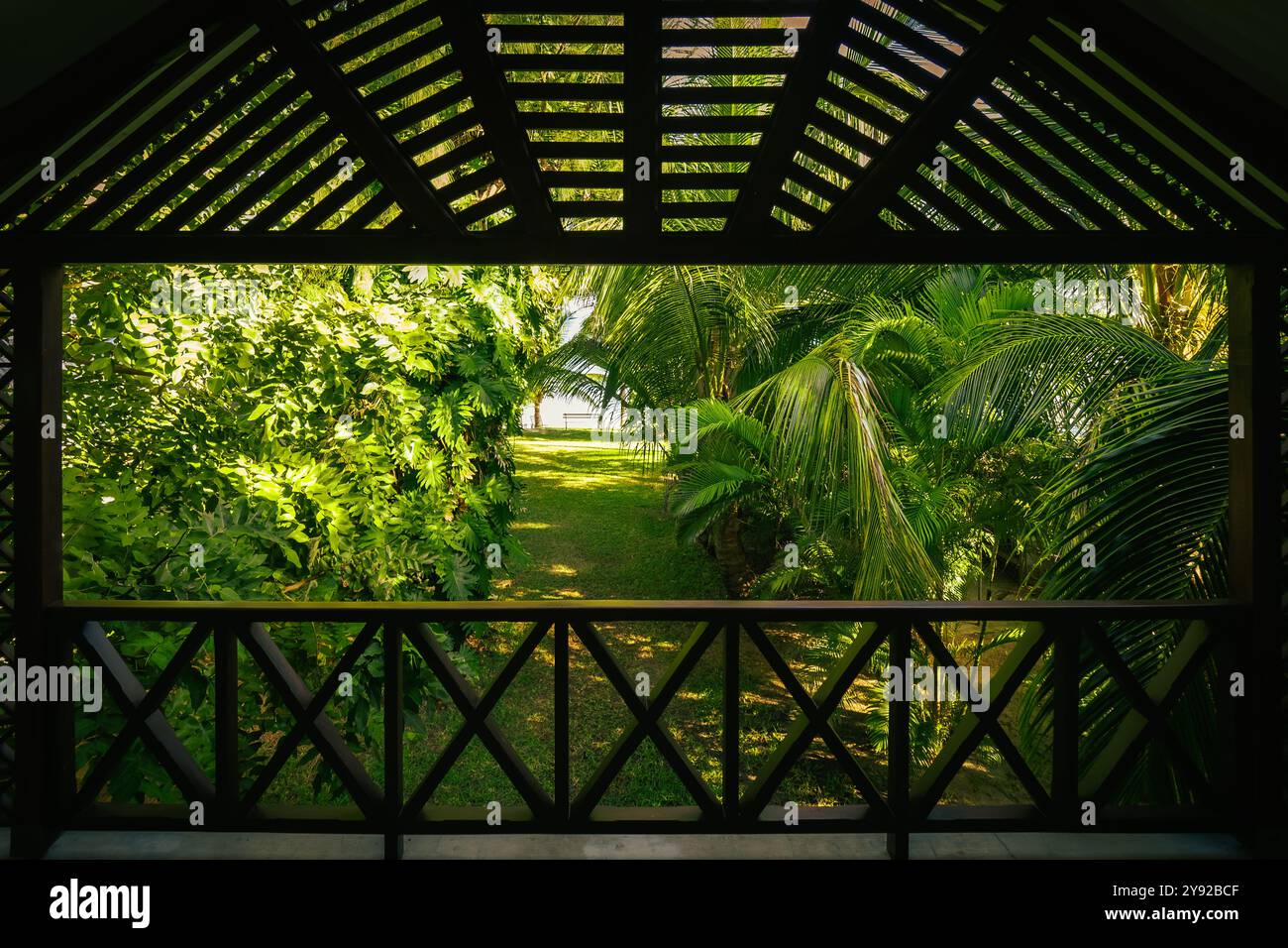 Belle vue sur un jardin tropical exotique avec un feuillage luxuriant au bord de la mer, vu d'un porche en bois surélevé, Grand Baie, Maurice Banque D'Images