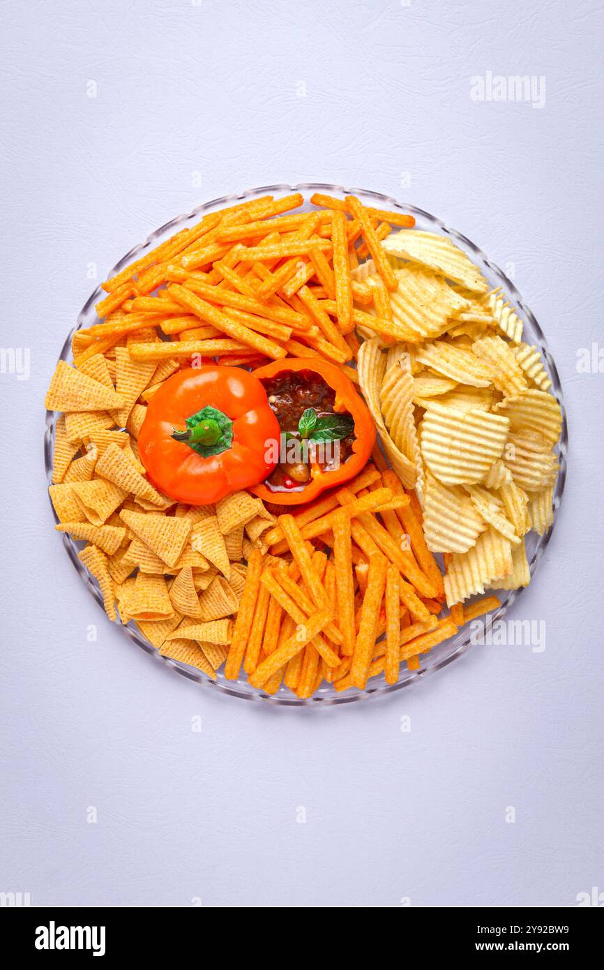 Un plateau de collation vibrant avec une variété de chips et de trempettes, présenté dans un bol décoratif de poivron Banque D'Images