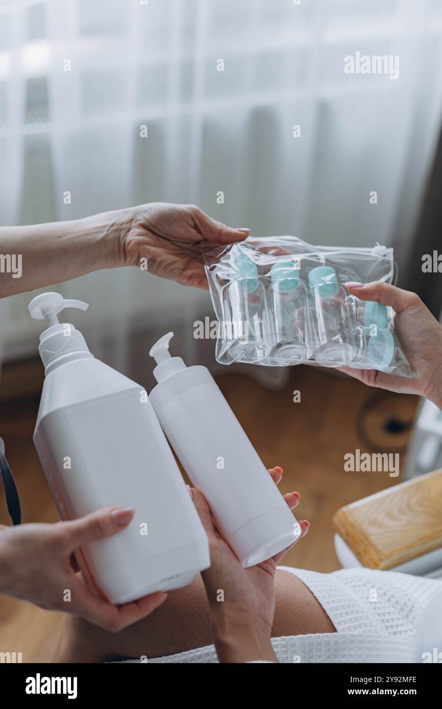Cosmétologue montre au client un produit cosmétique et des bouteilles en plastique de voyage, maquette de bouteille de crème. Photo de haute qualité Banque D'Images